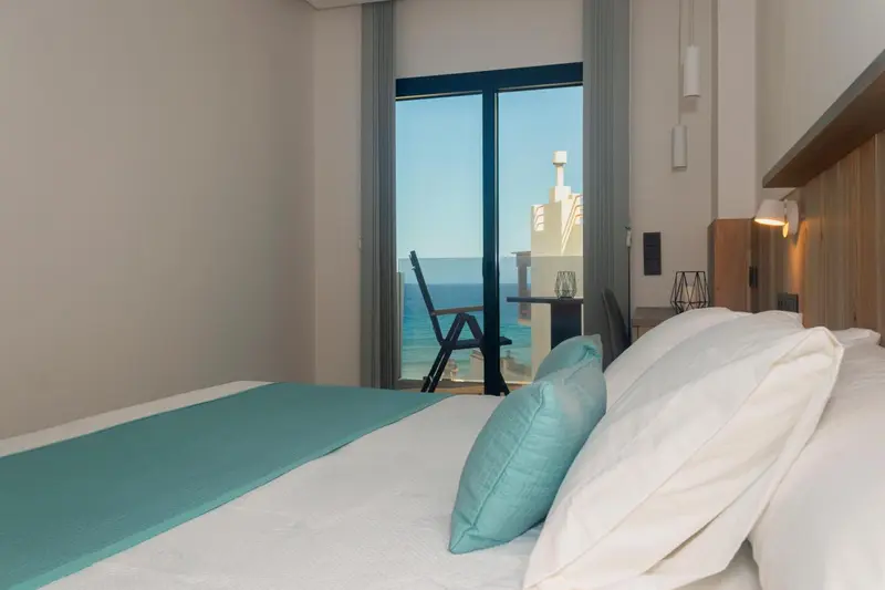 Une chambre lumineuse avec un lit fait donnant sur la mer.