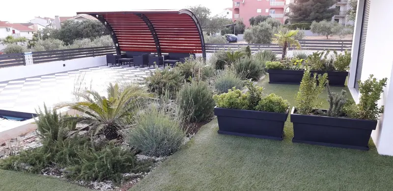 Terrasse aménagée avec mobilier de jardin et végétation luxuriante.