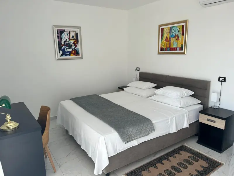 Une chambre lumineuse avec un grand lit recouvert d'une couverture grise.