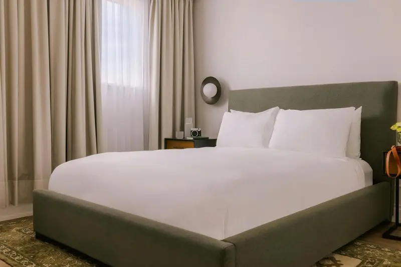 Une chambre avec un grand lit recouvert de draps blancs.