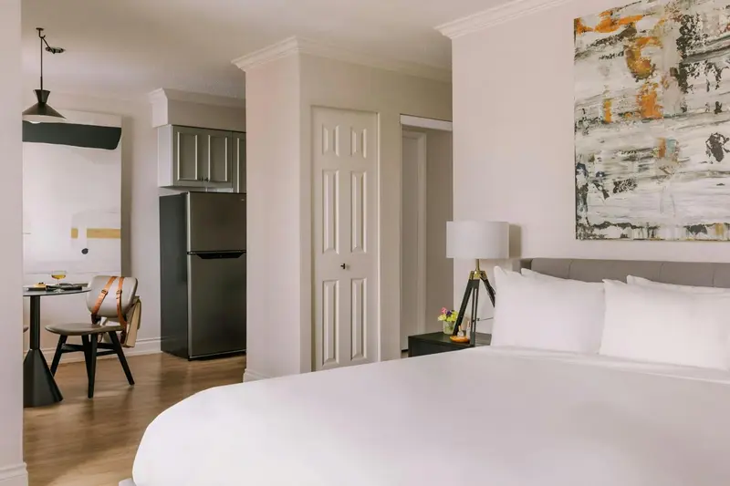 Une chambre lumineuse avec un lit et un coin cuisine.