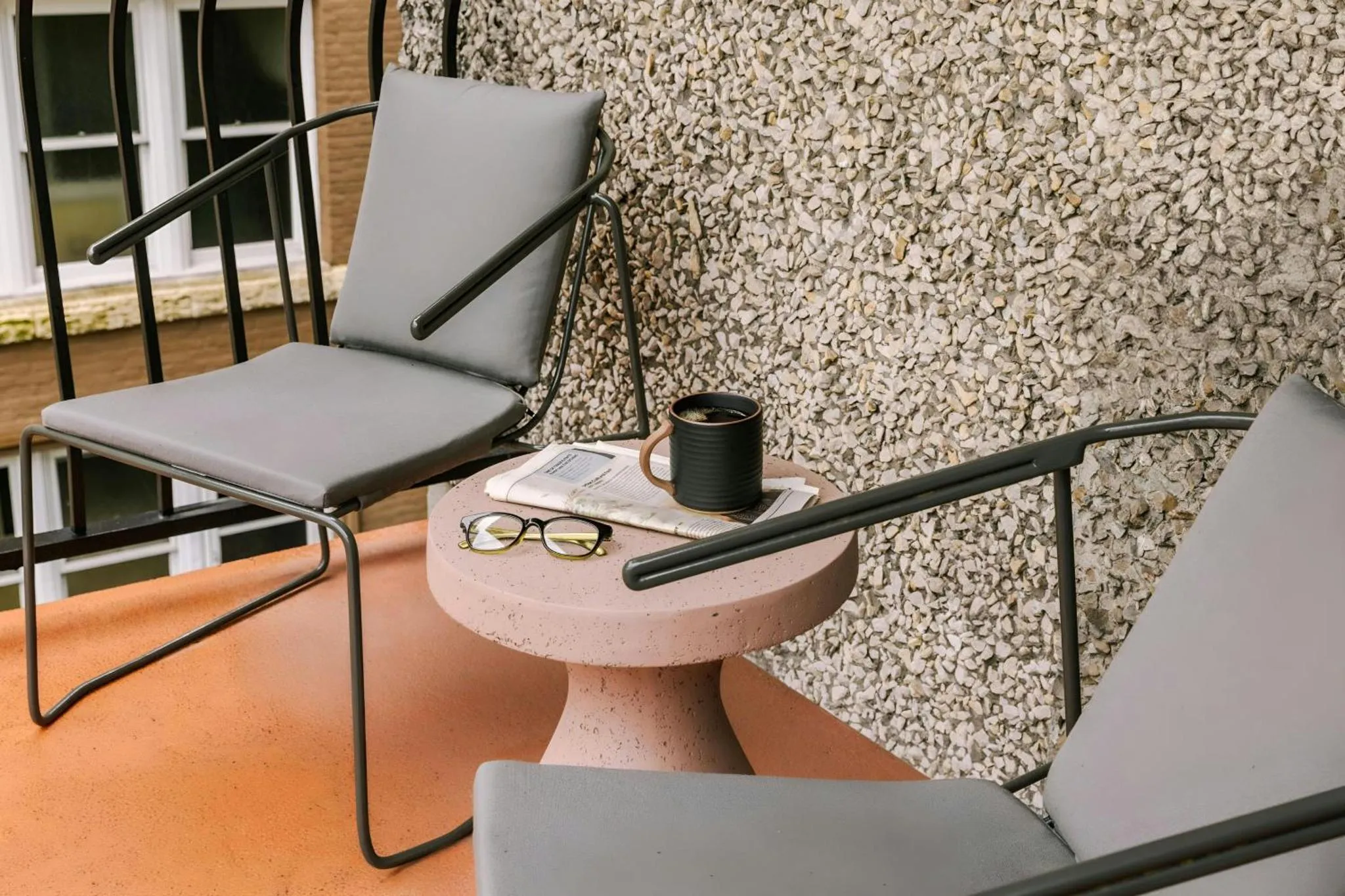 Deux fauteuils et une table d'appoint sur une terrasse.