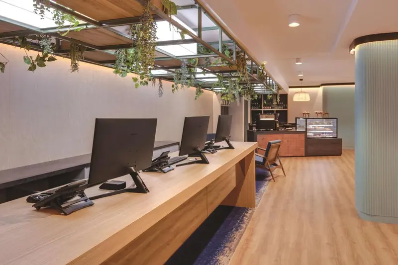 Un comptoir d'accueil moderne avec des ordinateurs et une vitrine réfrigérée.