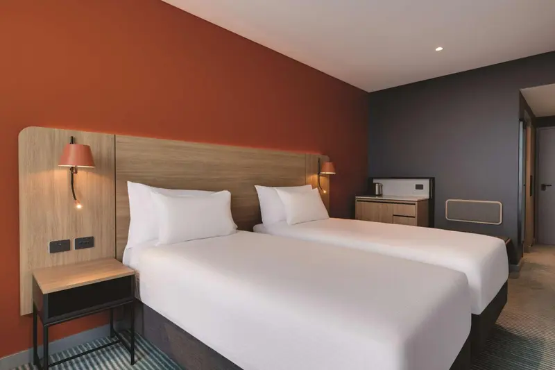 Une chambre d'hôtel moderne avec un grand lit blanc et des murs colorés.
