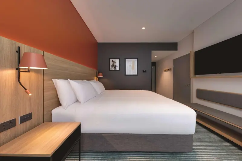 Une chambre moderne avec un grand lit blanc et des murs décorés.