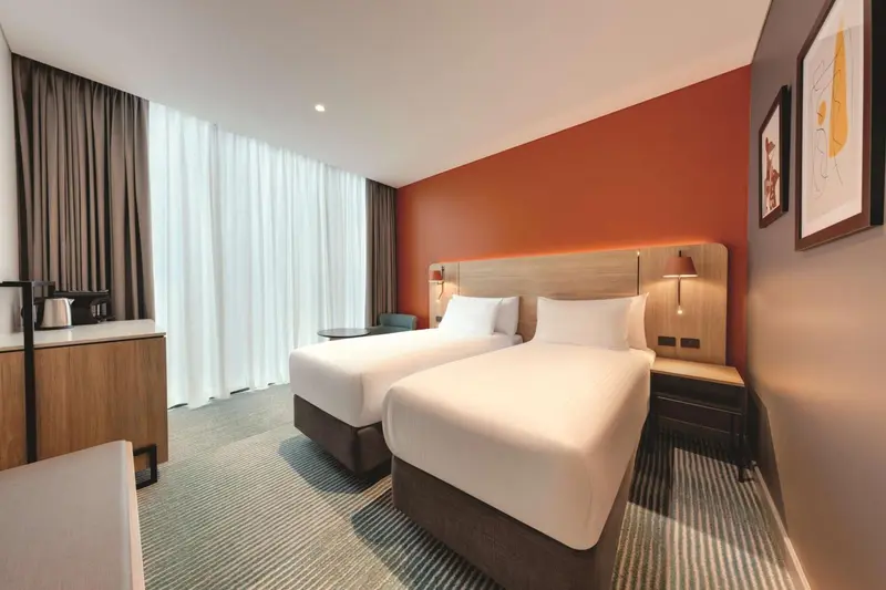 Chambre avec deux lits simples et un mur orange.