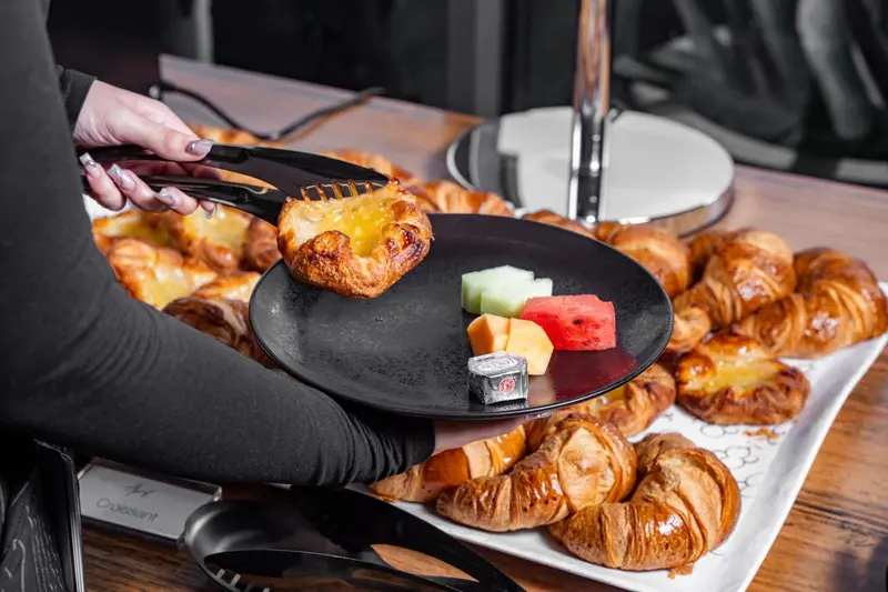 Une personne présente une assiette de viennoiseries et de fruits.