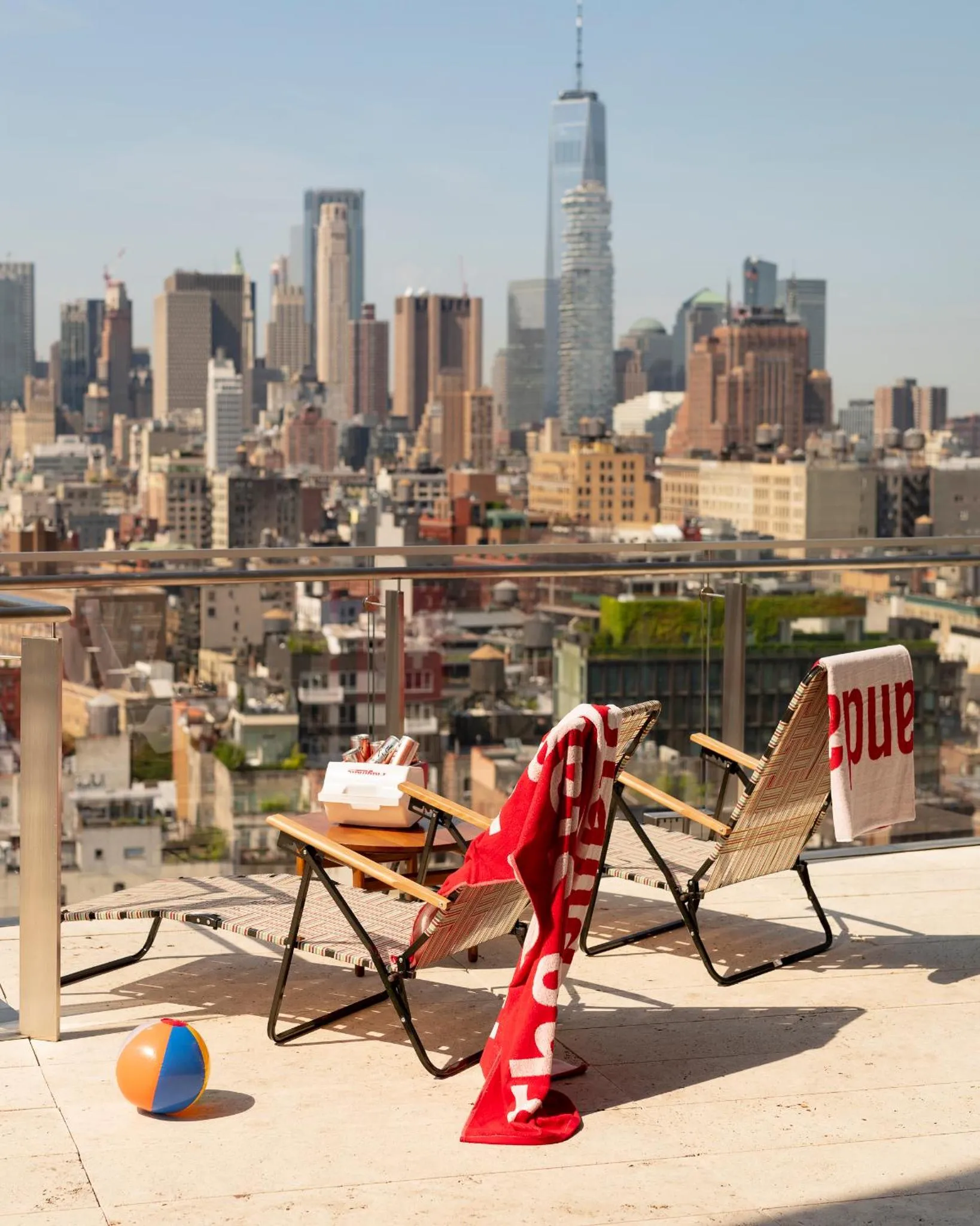 Deux transats et une balle sur une terrasse ensoleillée avec vue sur la ville.