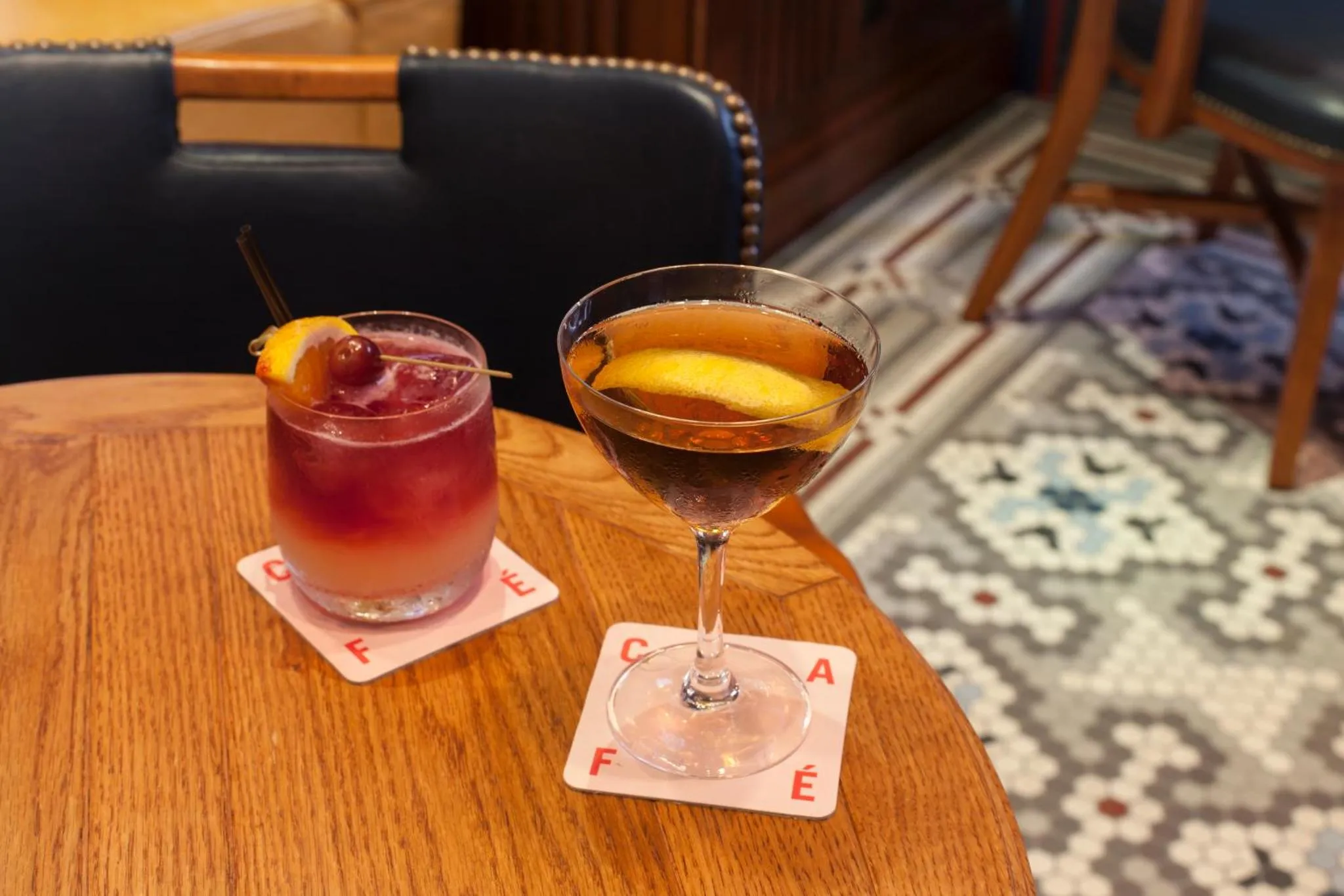 Deux cocktails colorés sont servis sur une table en bois.