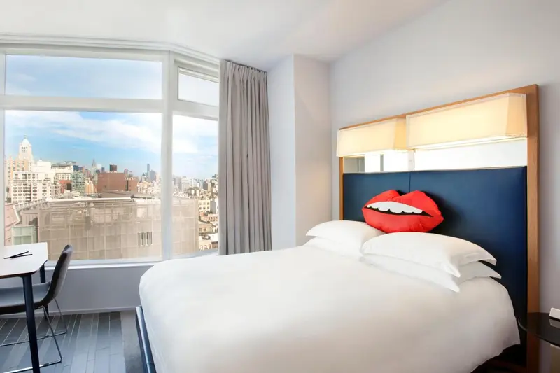 Une chambre lumineuse avec un grand lit et une vue sur la ville.