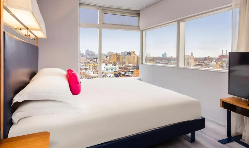 Une chambre lumineuse avec un grand lit et une vue sur la ville.