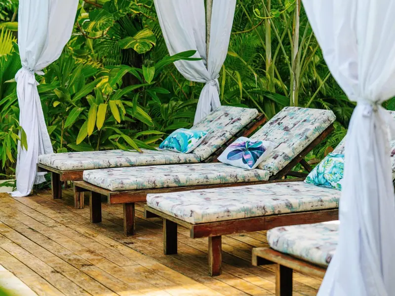 Transats et parasols blancs sur une terrasse en bois.