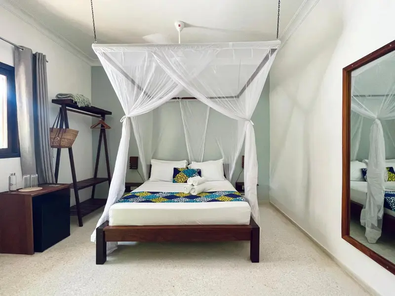 Une chambre lumineuse avec un lit à baldaquin et une décoration sobre.