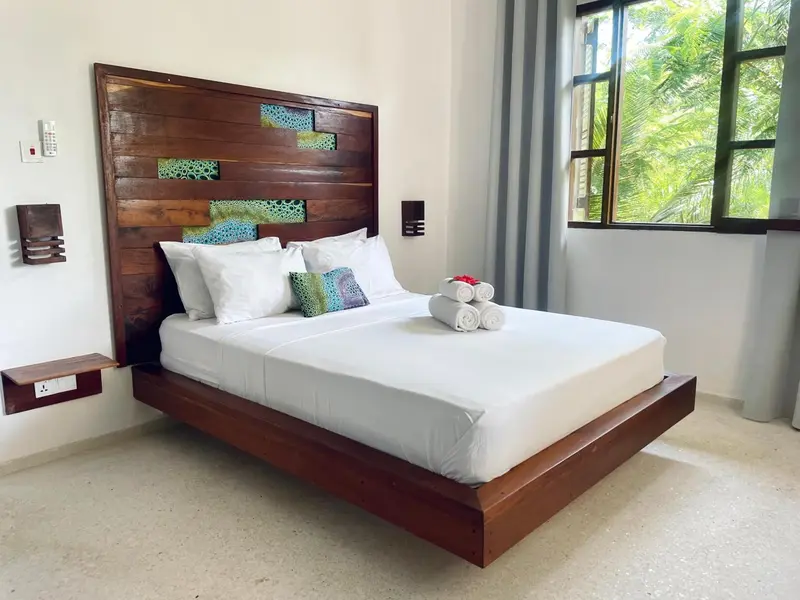 Une chambre lumineuse avec un grand lit et une décoration murale en bois.
