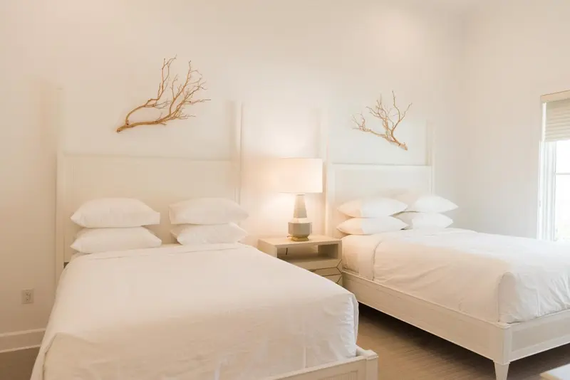 Deux lits simples avec des oreillers blancs dans une chambre lumineuse.