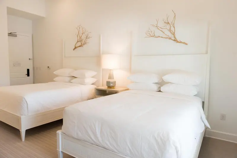 Deux lits simples avec des oreillers blancs dans une chambre lumineuse.