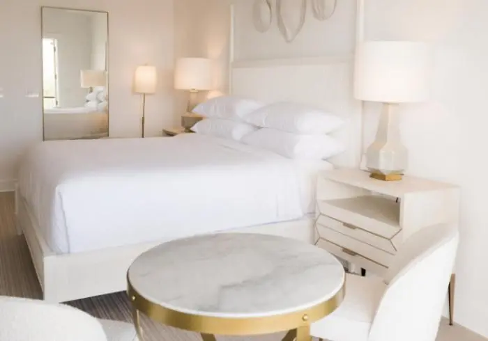 Une chambre lumineuse avec un grand lit recouvert de linge blanc.