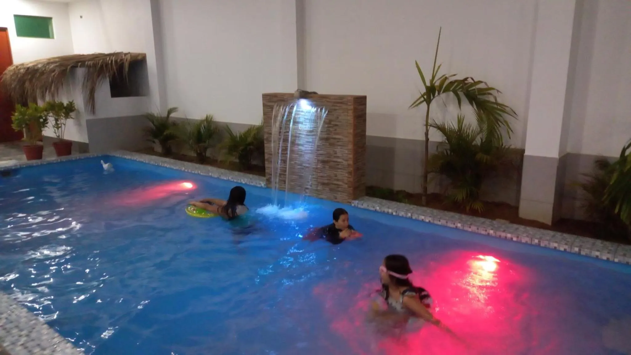 Une piscine illuminée avec des personnes se relaxant dans l'eau.