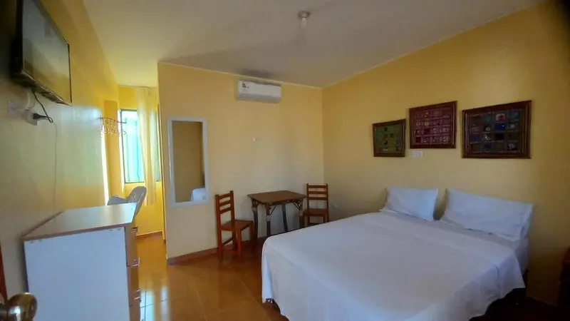 Une chambre lumineuse avec un lit, une table et une télévision.