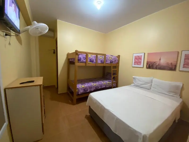 Une chambre avec un lit superposé et un grand lit blanc.