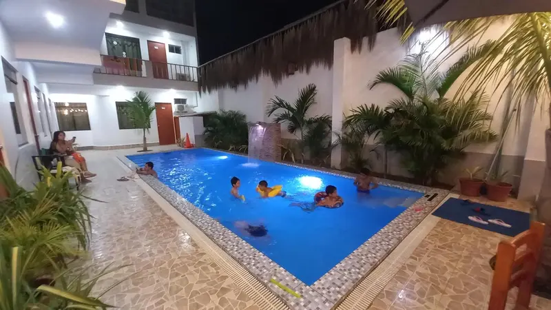 Une piscine rectangulaire bordée de chaises longues et de plantes tropicales.