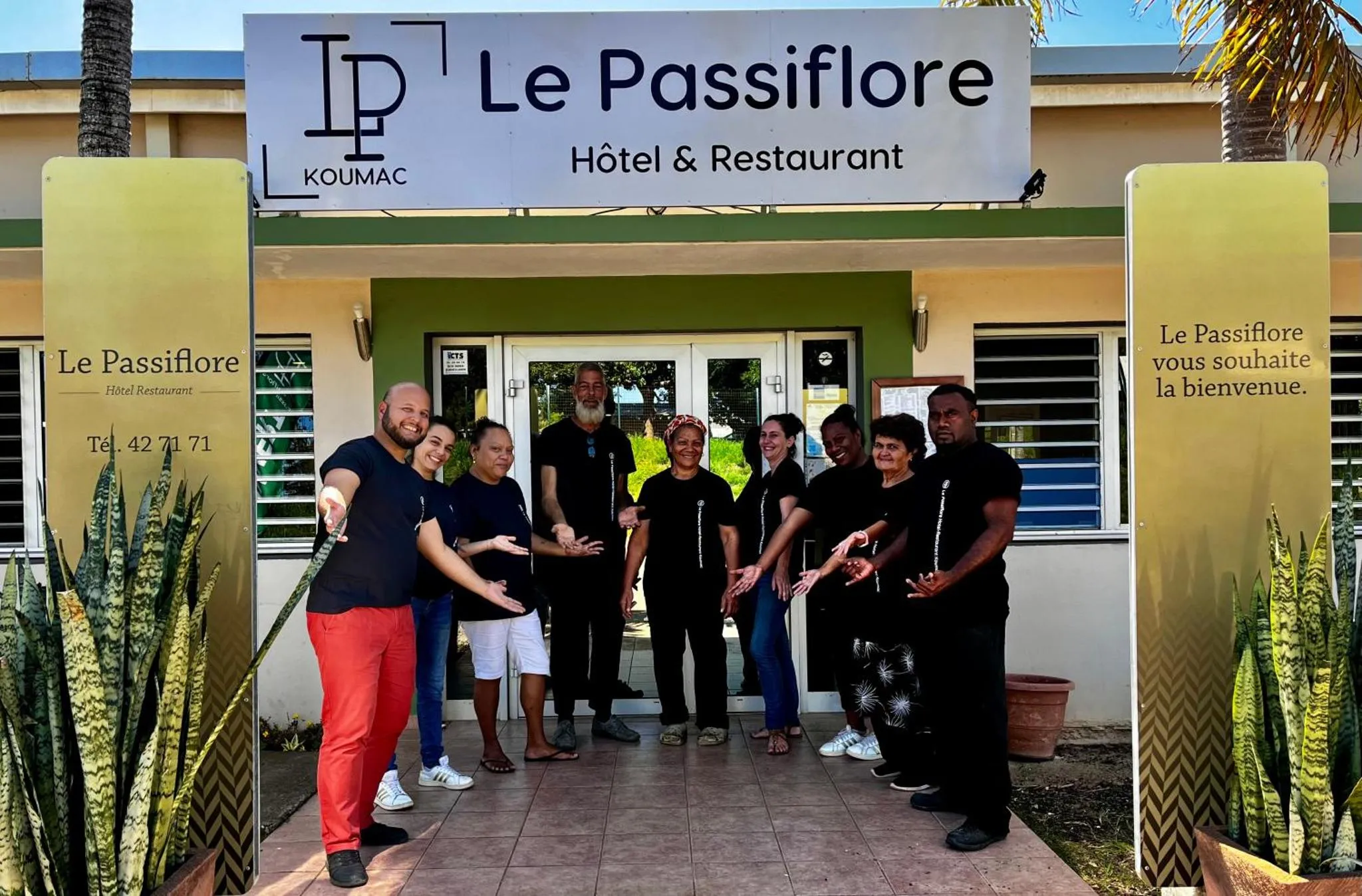 Un groupe de personnes souriantes se tient devant l'entrée d'un bâtiment.