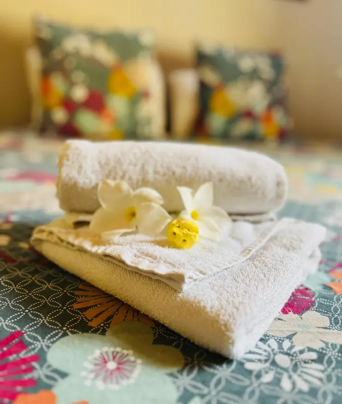 Serviettes pliées et fleur ornant un lit décoré de coussins colorés.