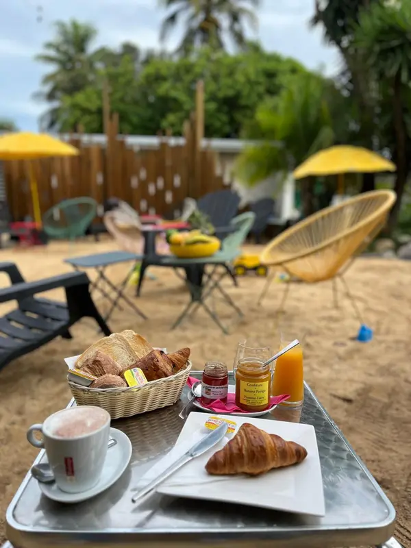 Un petit-déjeuner est servi sur une table en métal au sable.