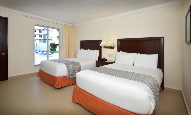 Chambre avec deux lits jumeaux et vue sur une piscine.