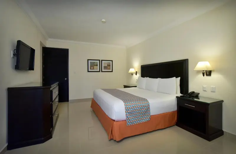 Une chambre d'hôtel lumineuse avec un grand lit et une télévision.