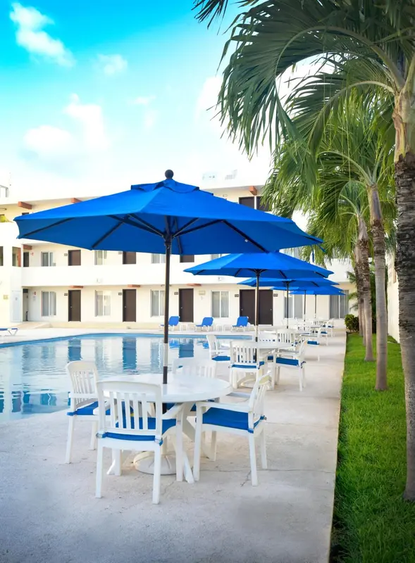 Terrasse avec tables et chaises près d'une piscine ensoleillée.