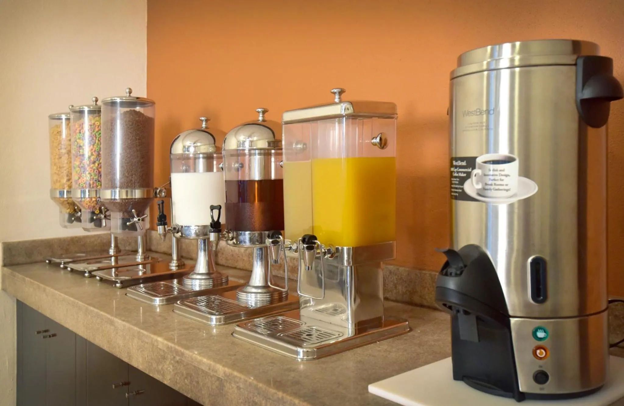 Une sélection de boissons et de céréales en libre-service est présentée sur un comptoir.