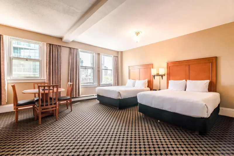 Une chambre d'hôtel lumineuse avec deux lits et un coin repas.