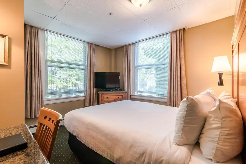 Une chambre lumineuse avec un lit fait et un bureau près de la fenêtre.