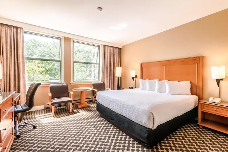 Une chambre d'hôtel lumineuse avec un grand lit et un coin salon près de la fenêtre.
