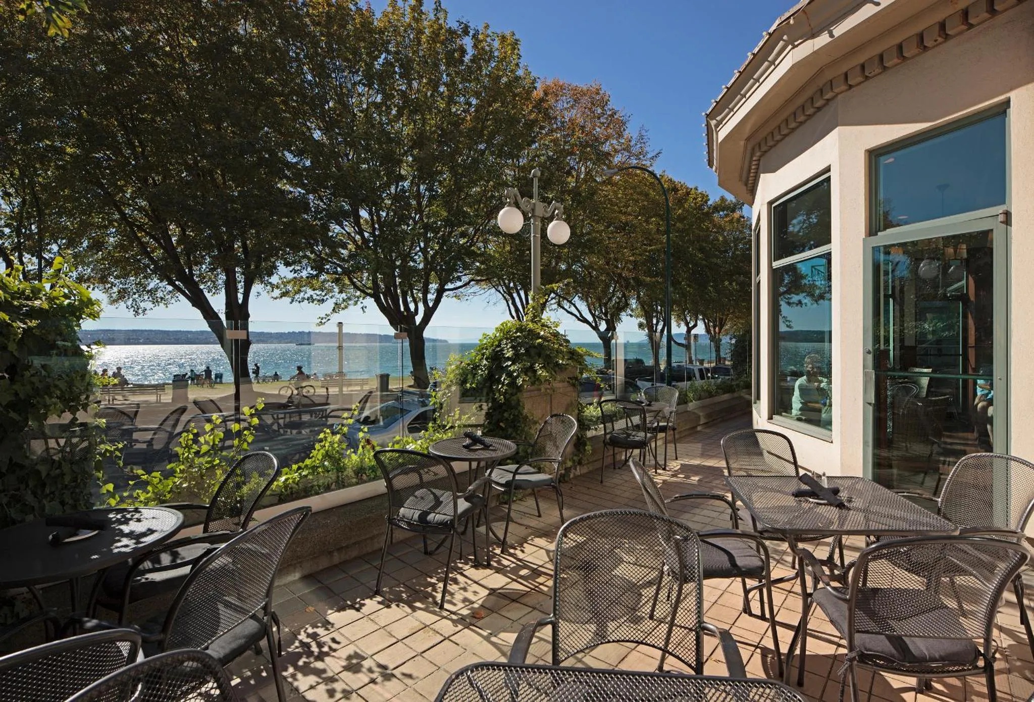 Terrasse ombragée avec tables et chaises en bord de mer.