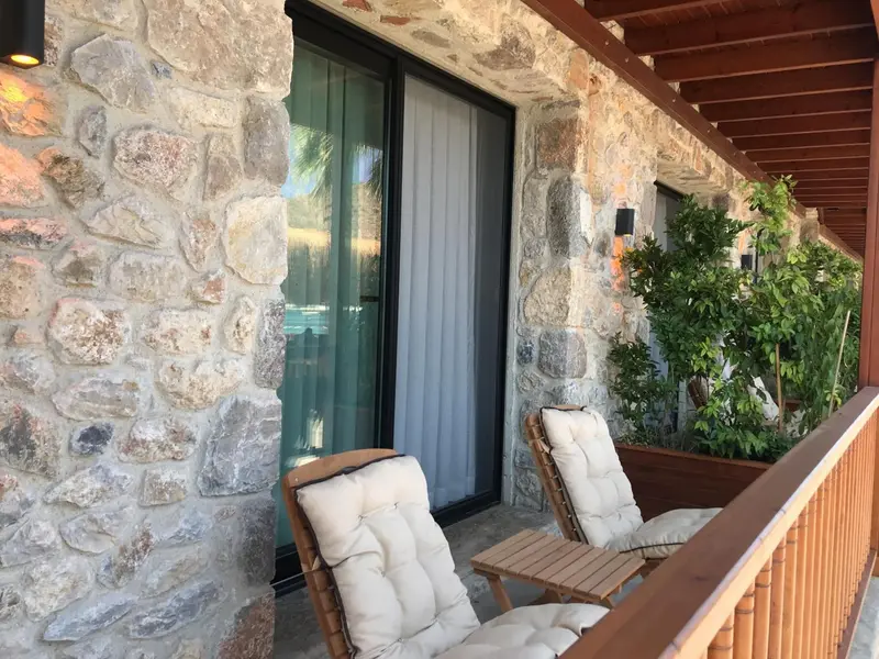 Terrasse avec mobilier d'extérieur devant un mur en pierre.