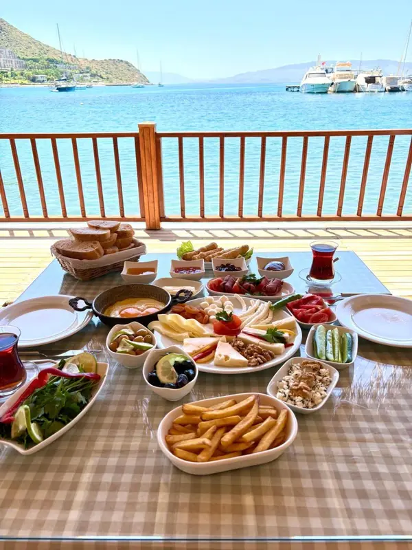 Une table est dressée avec un copieux petit-déjeuner face à la mer.