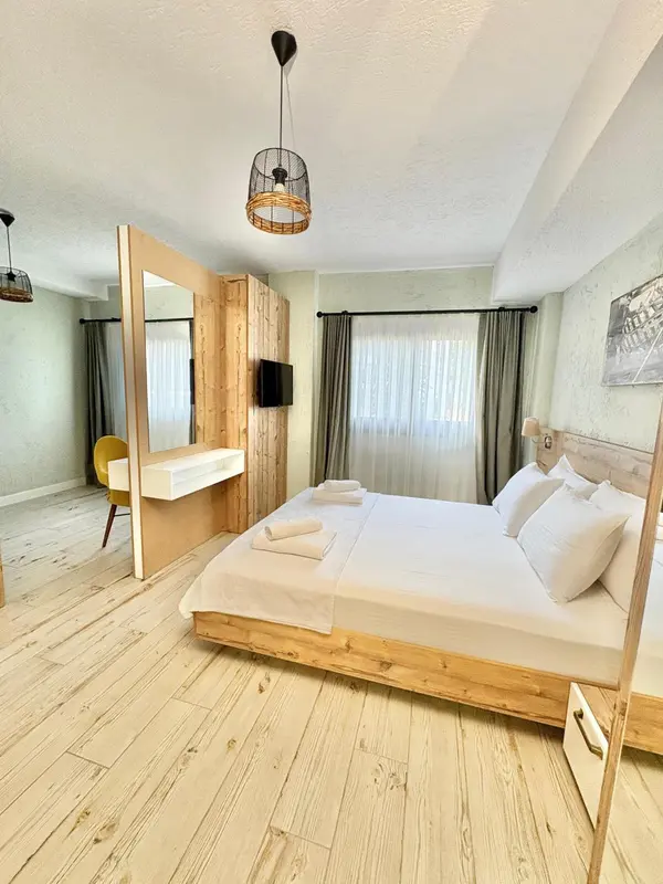 Une chambre lumineuse avec un grand lit et un espace coiffeuse.