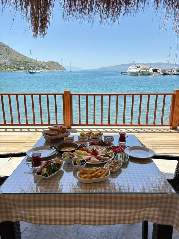 Une table dressée pour le petit-déjeuner en terrasse avec vue sur la mer et les bateaux.