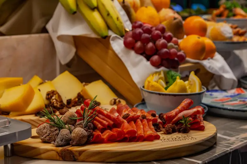 Présentation de fruits frais, de fromages et de charcuteries sur un buffet.