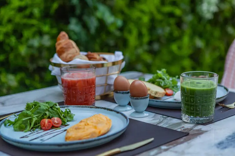Une table est dressée avec un petit-déjeuner composé de viennoiseries, d'œufs et de jus de fruits.