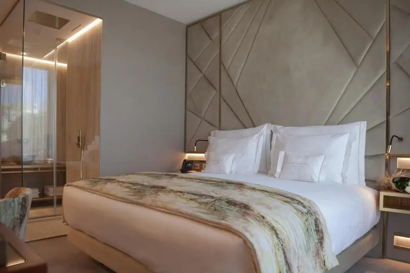 Une chambre moderne avec un grand lit et une salle de bain vitrée.
