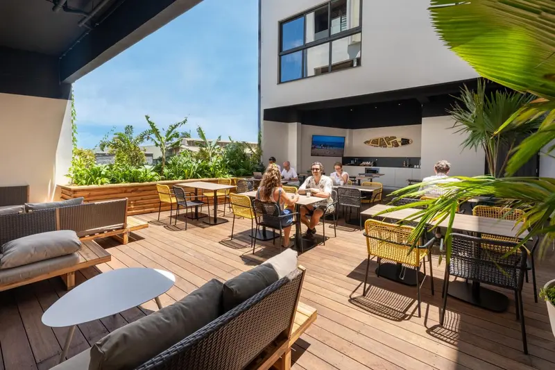 Terrasse aménagée avec tables, chaises et canapés en osier.