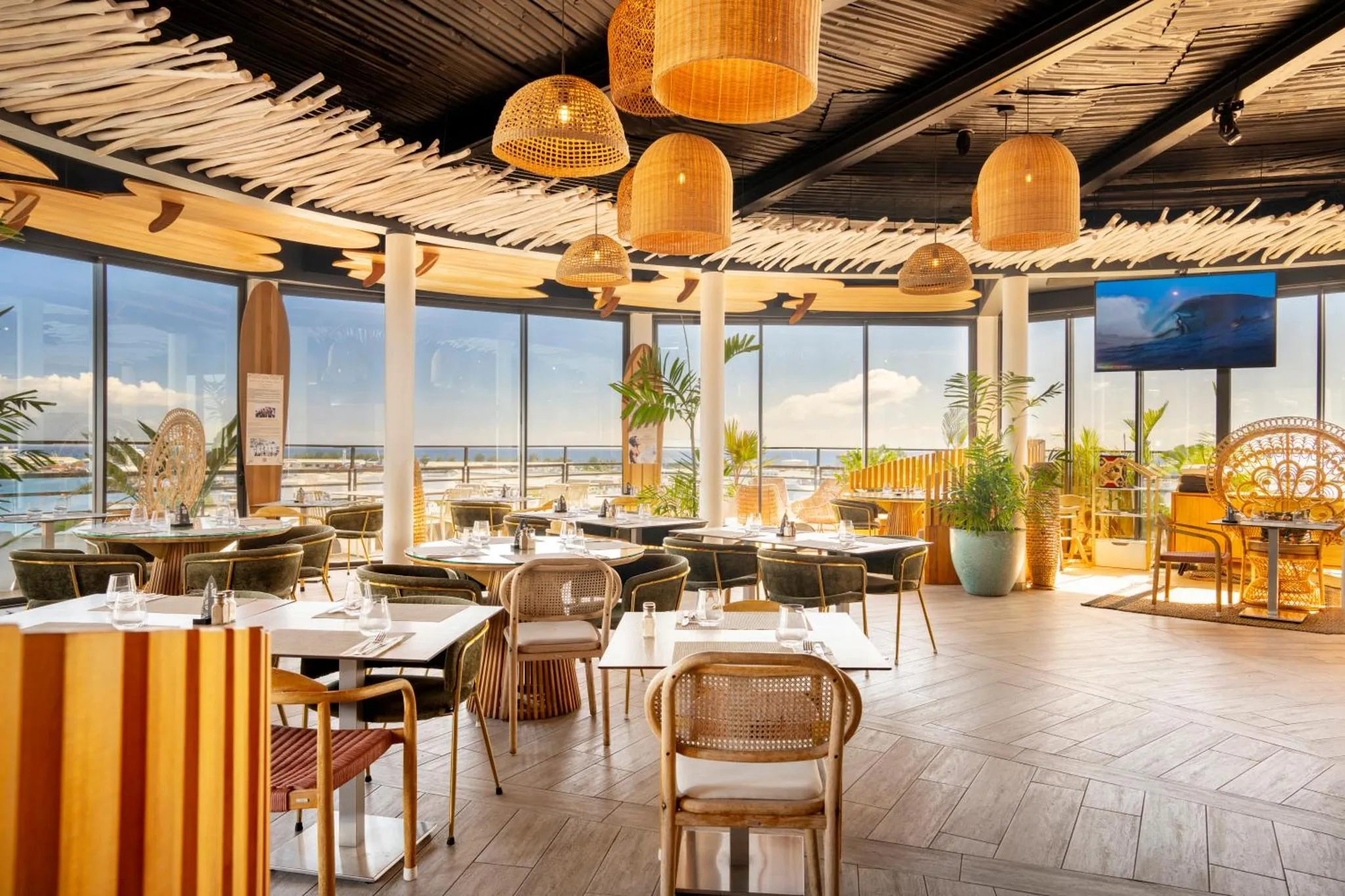 Une salle lumineuse avec des tables dressées et une vue sur la mer.