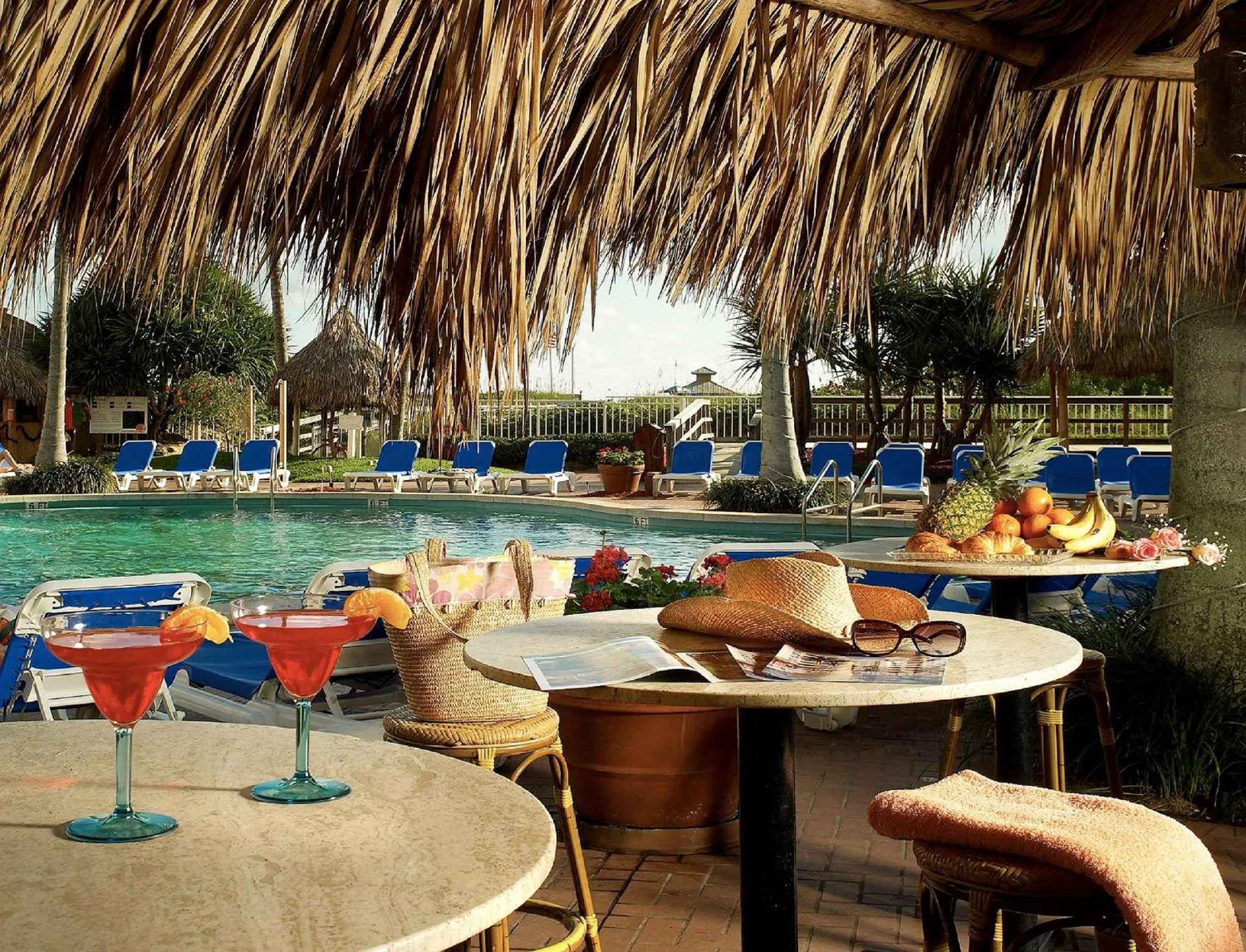 Une table est dressée avec des boissons et des fruits près d'une piscine.