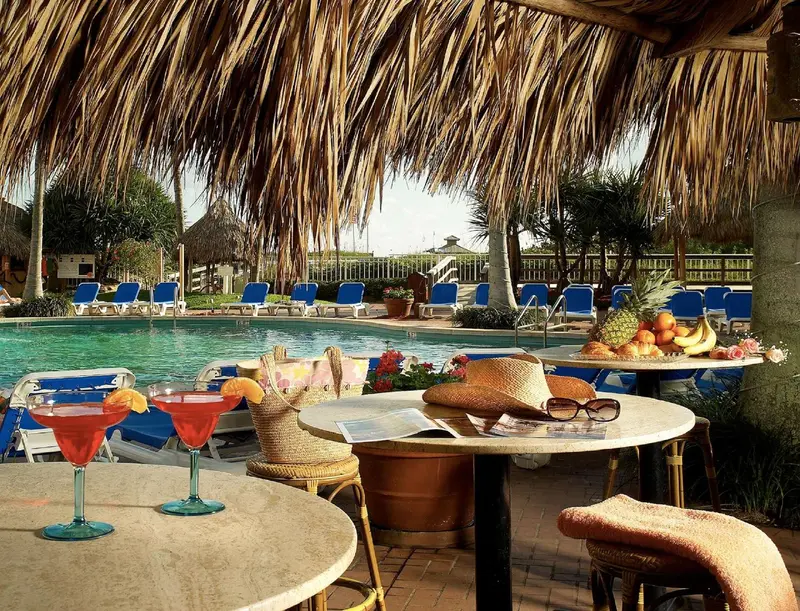 Une table est dressée avec des boissons et des fruits près d'une piscine.