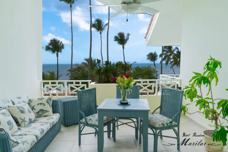 Terrasse aménagée avec salon et table donnant sur la mer et la végétation.