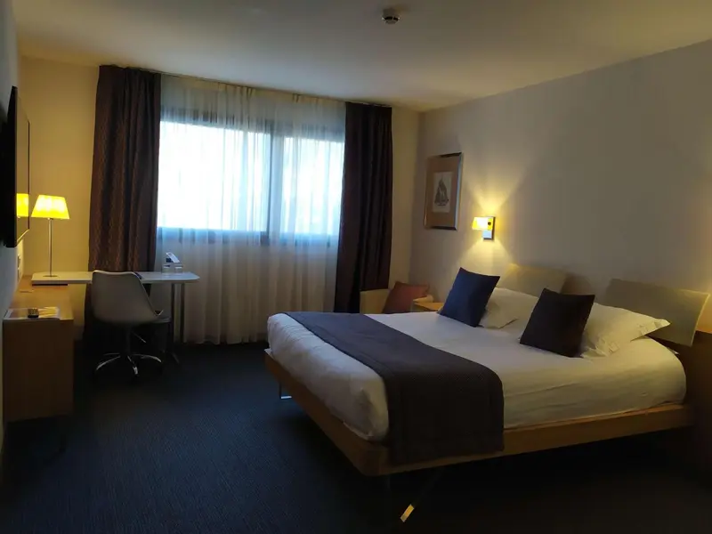 Une chambre d'hôtel lumineuse avec un grand lit et un bureau.