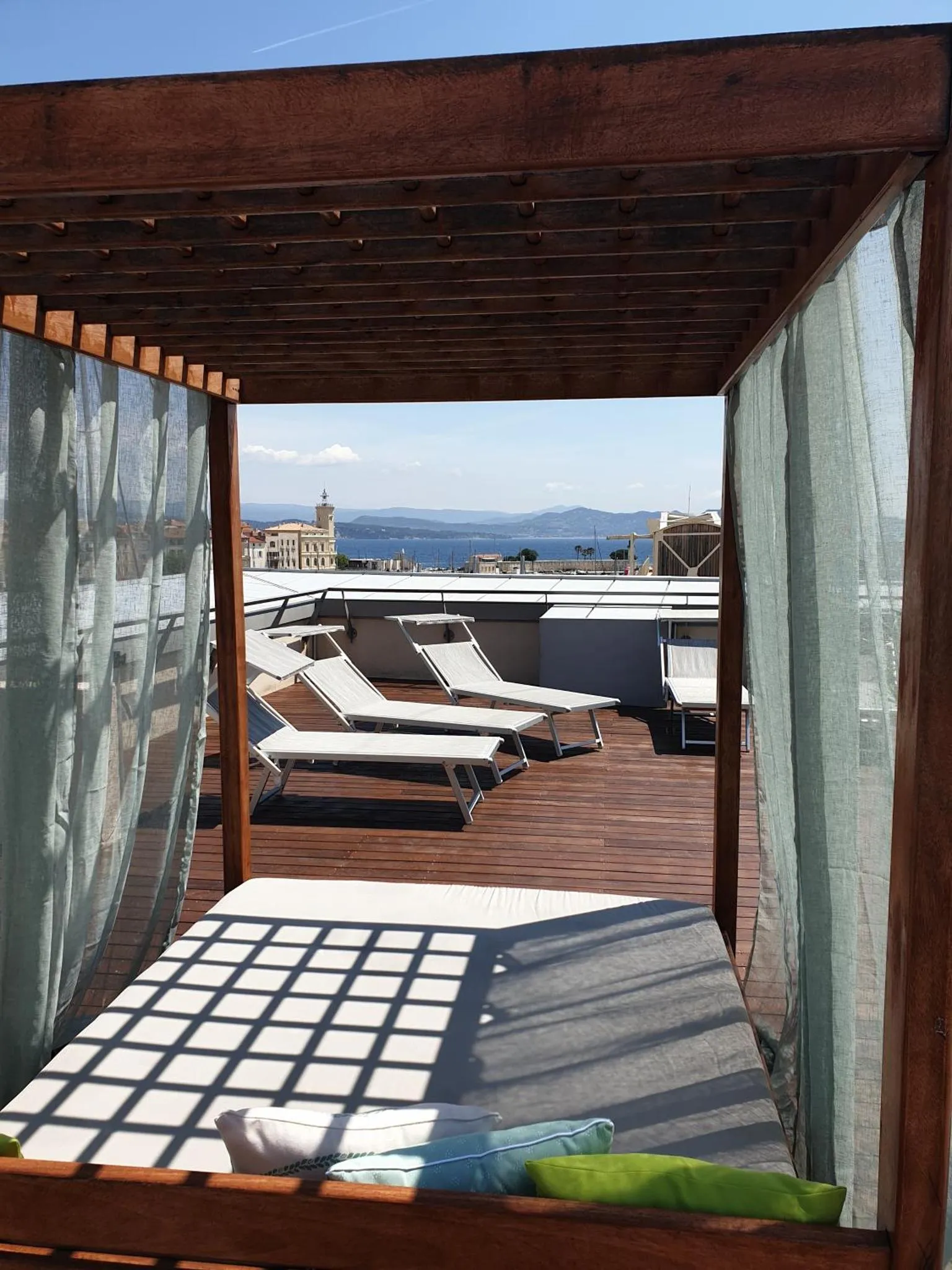 Terrasse ombragée avec transats et vue sur la mer.